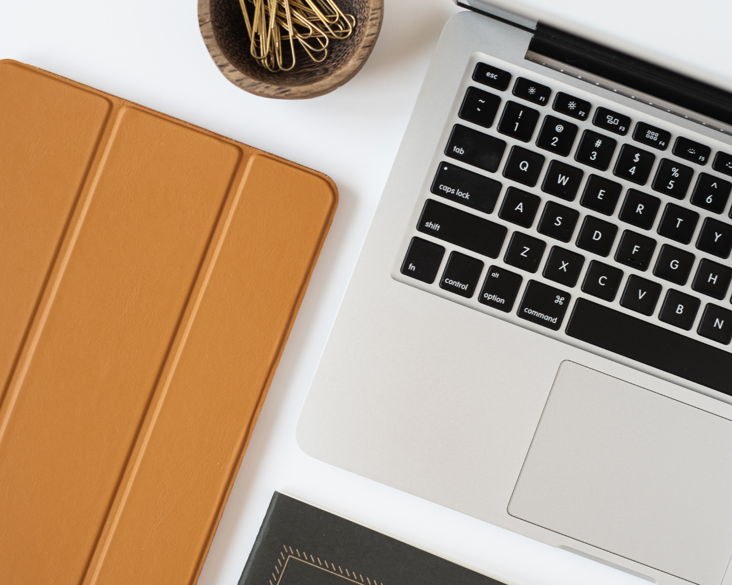 5 Things You Must Include in Your Business Coaching Contract - Flatlay image of computer, tablet in a brown leather case and notebook
